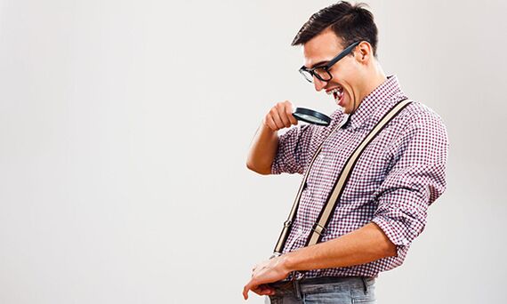 A man looks at his penis through a magnifying glass with the desire to increase its size